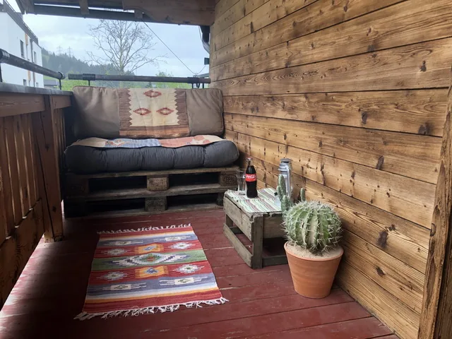 Balkon met een houten wand en een kleurrijk kleed